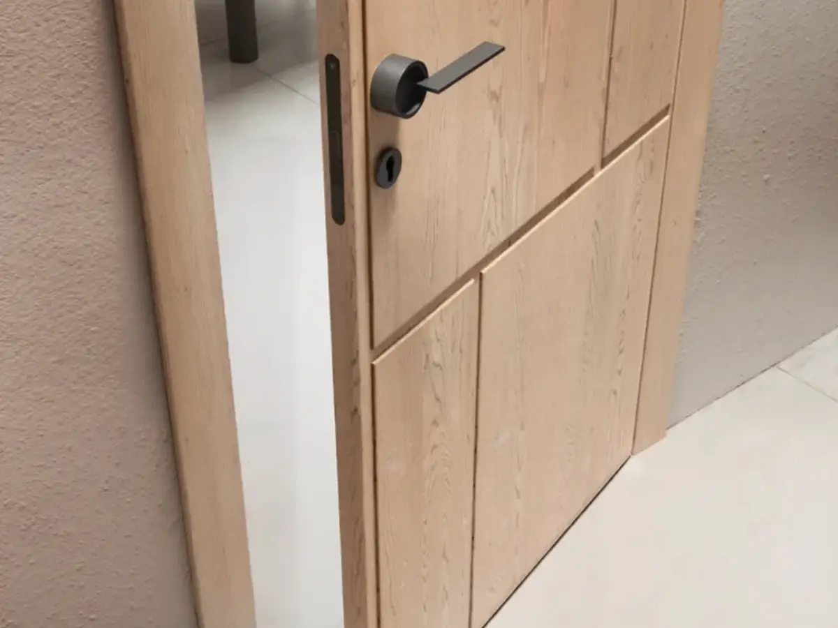 Custom light oak interior door with black lever handle and matching wood trim