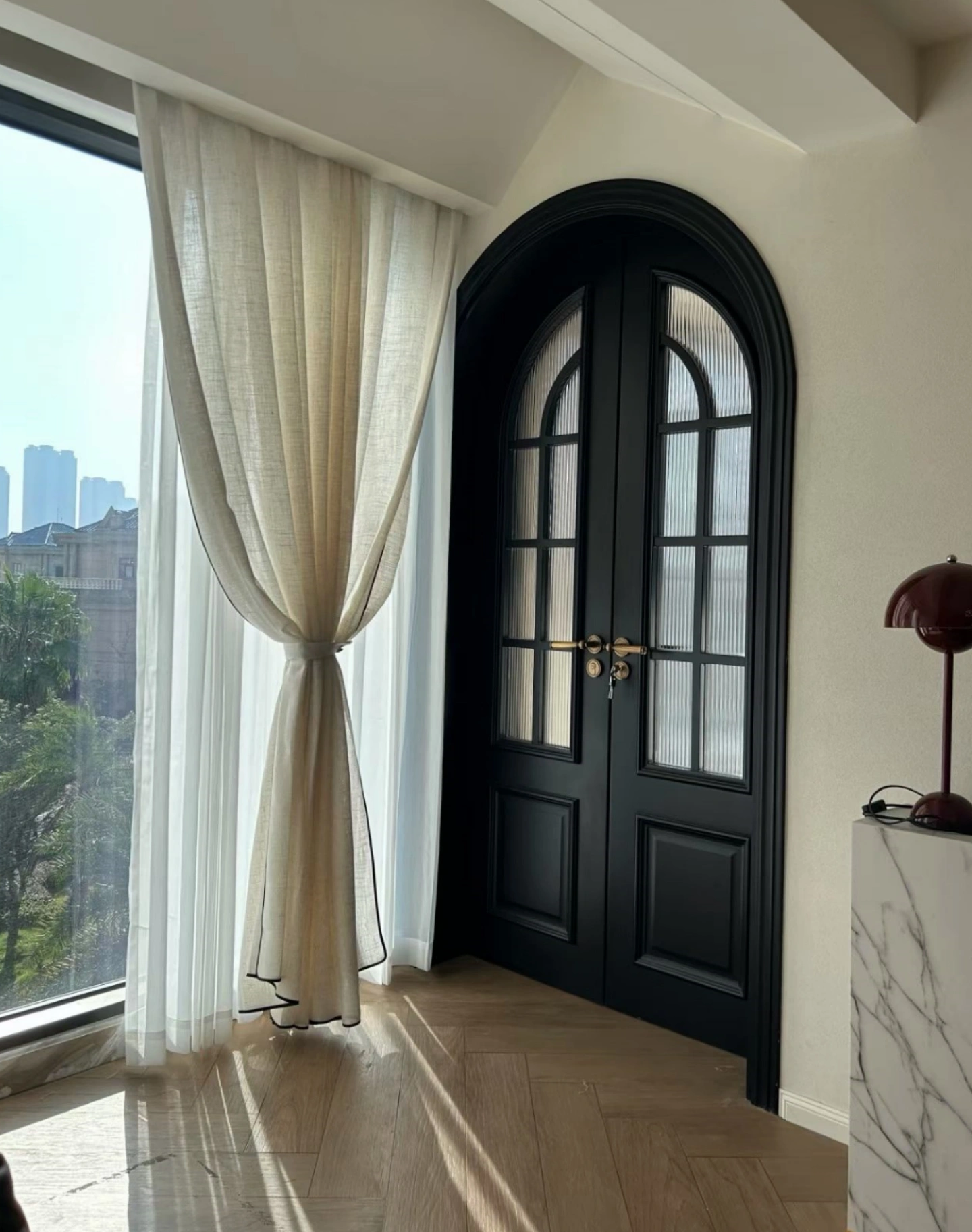 Custom arched black entry door with luxury interior millwork in Singapore residence